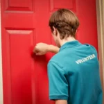Young political canvasser knocking on a red door.